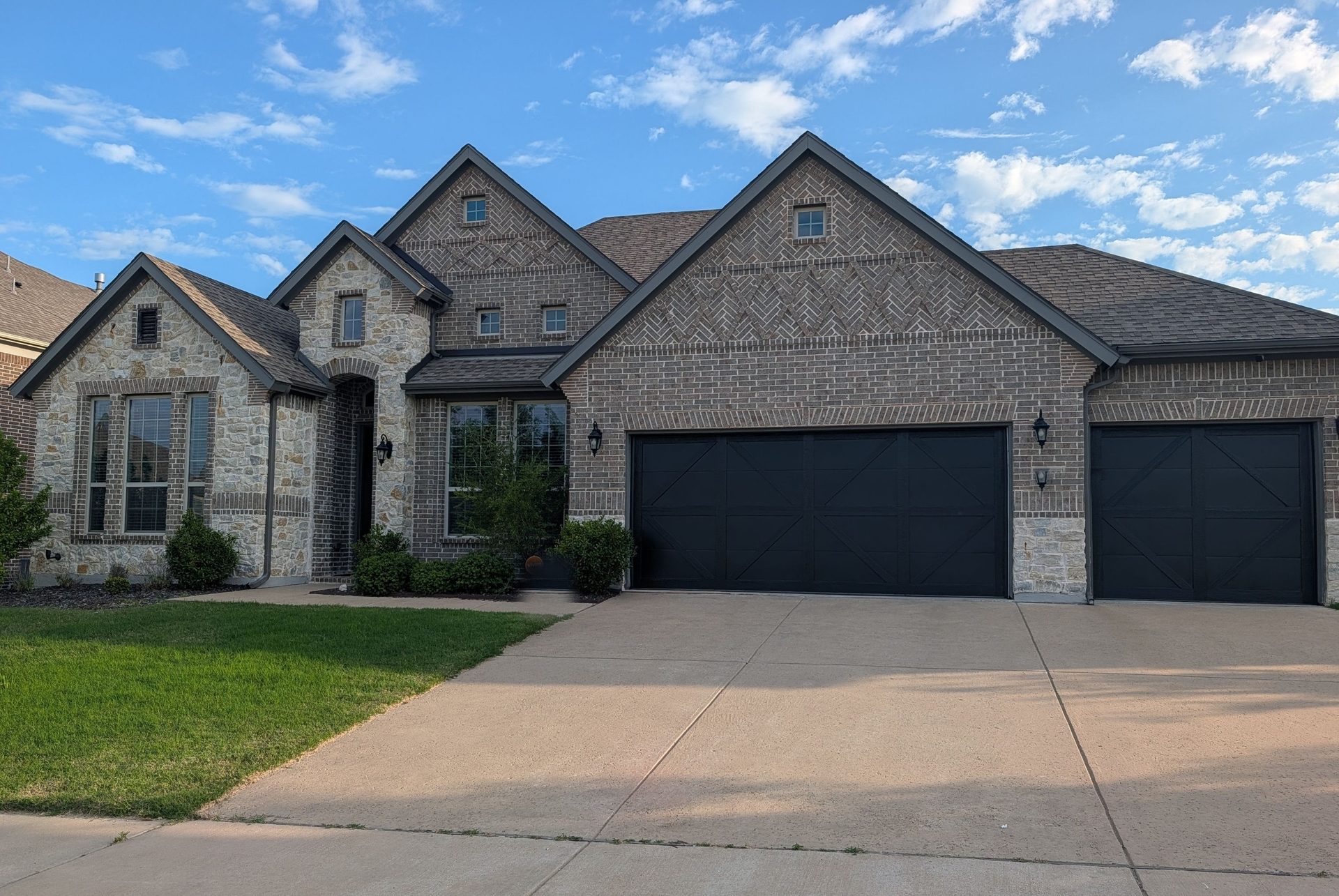 Three premium black carriage-style garage doors installed by Dad's Garage Doors on an upscale Dallas-Fort Worth home